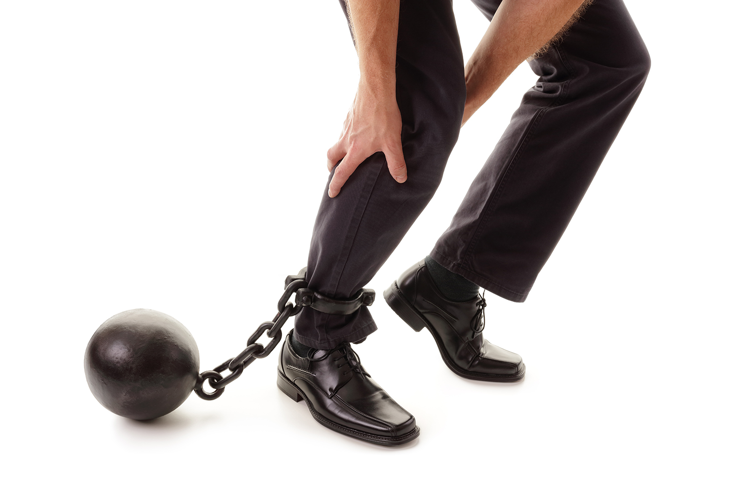 Ball and chain restraining a businessman as he tries to walk concept for business burden, willpower and determination
